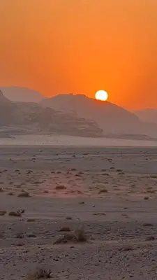 a sunset in the desert with a mountain in the background at Enad wadirum camp in Wadi Rum
