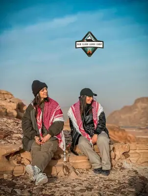 two men sitting on a rock with a sign on it at RUM ELARA lUXRY CAMP in Wadi Rum