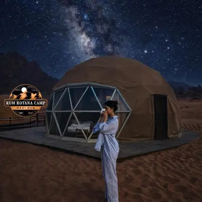 a woman talking on a cell phone in front of a tent at WADi RUM ROTANA BUBBLE lUXURY CAMP in Wadi Rum
