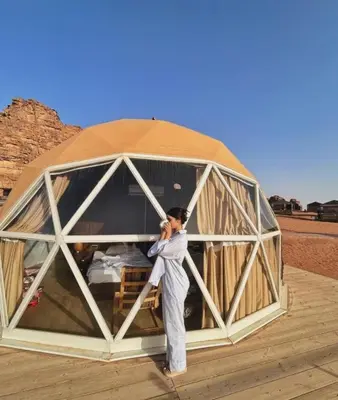 a woman is standing inside of a tent at WADi RUM ROTANA BUBBLE lUXURY CAMP in Wadi Rum