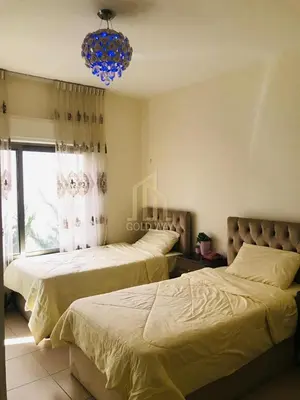 two beds in a bedroom with a chandelier at Chic 2-Bedroom - Fully Furnished in Amman