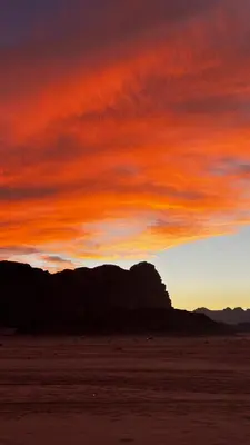 a sunset in the desert with a red sky at Wadi Rum Royal Camp in Disah