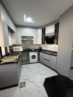 a kitchen with white cabinets and a washer and dryer at الكرك الثنية in Kerak