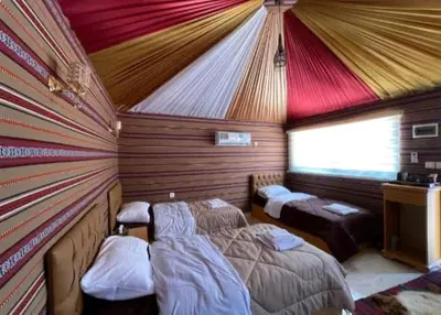a bedroom with two beds in a room with a roof at Wadi Rum Nomad Way Camp in Wadi Rum