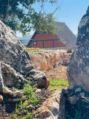 a stone wall with a red building in the background at The Branch Lodges in Ajloun