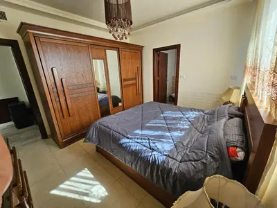 a bedroom with a bed and a wooden cabinet at MK7 - Two Bedroom Apartment in Amman