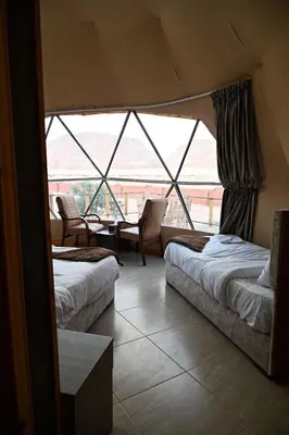 a room with two beds and a large window at Sultan Camp Wadi Rum in Wadi Rum