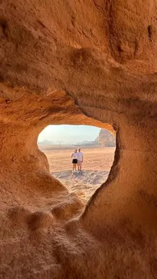 two people standing in a cave in the desert at Sultan Camp Wadi Rum in Wadi Rum