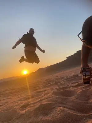 a man jumping in the desert at sunset at Sultan Camp Wadi Rum in Wadi Rum