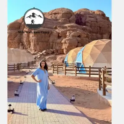 a woman standing in front of a sign in the desert at Mila Wadi Rum Camp in Wadi Rum