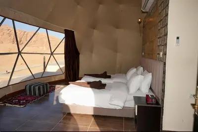 a bedroom with a bed and a large window at Wadi rum camp in Wadi Rum