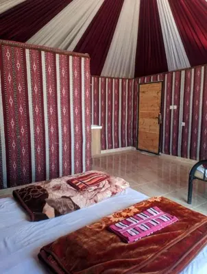 a bedroom with a bed with a red and white wall at Wadi rum camp in Wadi Rum