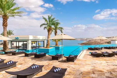 a resort with a swimming pool and palm trees at Hilton Dead Sea Resort & Spa in Sowayma