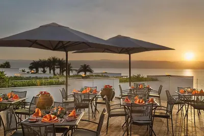 a restaurant with tables and chairs and umbrellas at Hilton Dead Sea Resort & Spa in Sowayma