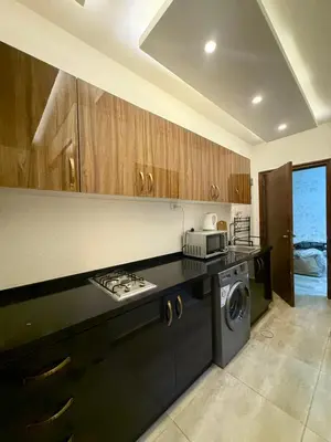 a kitchen with wooden cabinets and a washer and dryer at Swefieh studio 8 in Amman