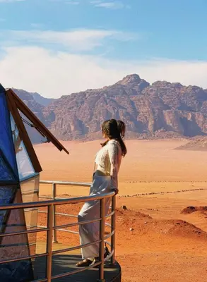 a woman standing on a fence looking out over the desert at Ahmad desert camp wadi rum in Wadi Rum