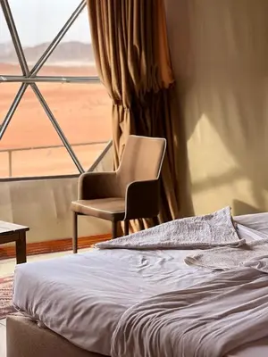 a bedroom with a chair and a bed and a window at Golden Stars Luxury Camp Wadi Rum in Wadi Rum