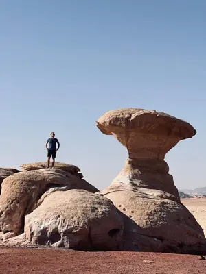 a man standing on top of two large rocks at Local experience in El Quweira