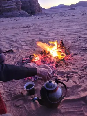 a person sitting next to a campfire in the desert at Wadi rum Breeze of calm in Wadi Rum