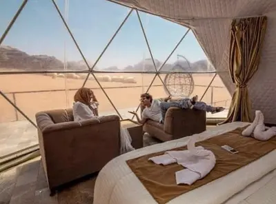 two people sitting in a room with a bed and a window at Nile Bedouin Camp in Disah