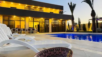 a house with a swimming pool with white chairs and a building at Villa W2 in Amman