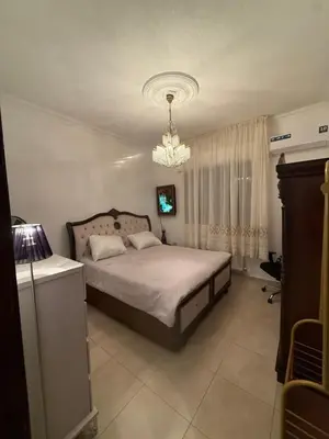 a bedroom with a bed and a chandelier at Furnished luxurious apartment with a stunning view near Kling Hussein Business Park in Amman