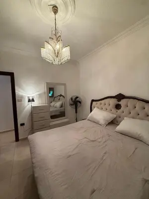 a bedroom with a large bed and a chandelier at Furnished luxurious apartment with a stunning view near Kling Hussein Business Park in Amman