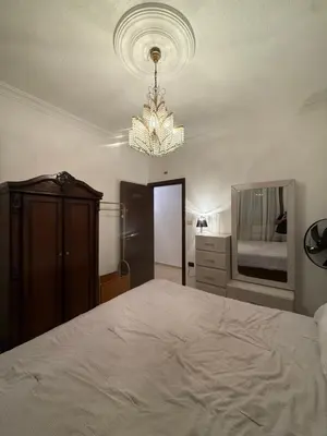 a bedroom with a large bed and a chandelier at Furnished luxurious apartment with a stunning view near Kling Hussein Business Park in Amman