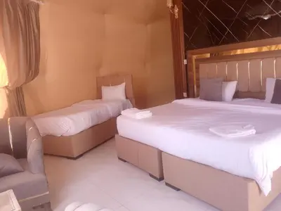 two twin beds in a room with a chair at Wadi Rum Adventure Camp & Tour in Wadi Rum