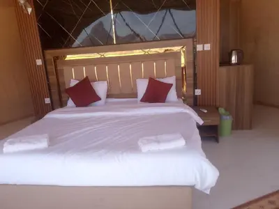 a bedroom with a large white bed with red pillows at Wadi Rum Adventure Camp & Tour in Wadi Rum