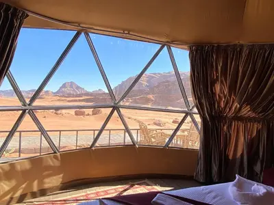 a bedroom with a large window with a view of the desert at Siella Pearl of Wadi Rum in Wadi Rum