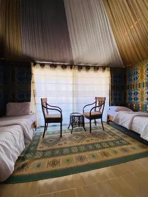a room with two beds and two chairs and a table at Siella Pearl of Wadi Rum in Wadi Rum