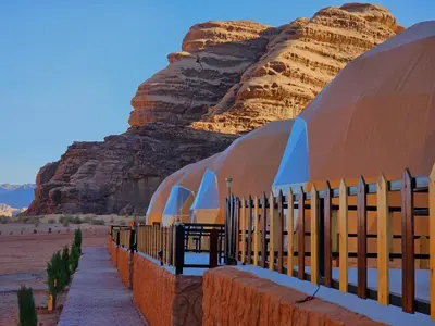 a building in the desert with a mountain in the background at Luxury Wadi Rum Camp in Wadi Rum