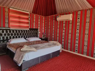 a bedroom with a bed in a room with red walls at Luxury Wadi Rum Camp in Wadi Rum