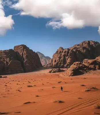 a person walking in the desert near some rocks at Luxury Wadi Rum Camp in Wadi Rum