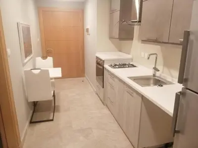 a small kitchen with a sink and a refrigerator at Pasha Holiday - DAMAC Tower in Amman