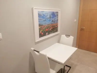 a white table and chairs in a room with a painting at Pasha Holiday - DAMAC Tower in Amman