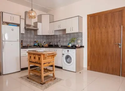 a kitchen with a white refrigerator and a washing machine at Weibdeh Oasis 2 Bedroom in Amman