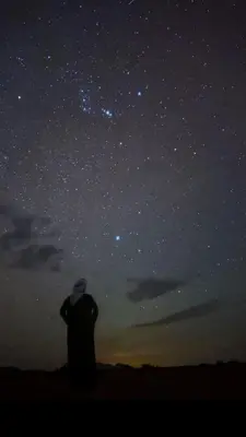 a man is looking up at the night sky at Silent Sands in Wadi Rum