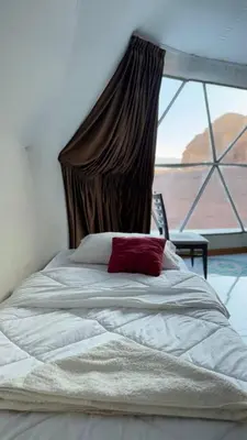 a bed in a bedroom with a large window at Silent Sands in Wadi Rum