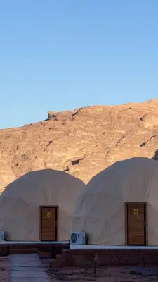 two domes in the desert with a mountain in the background at Silent Sands in Wadi Rum