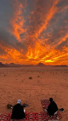 two people sitting on the beach watching the sunset at Silent Sands in Wadi Rum