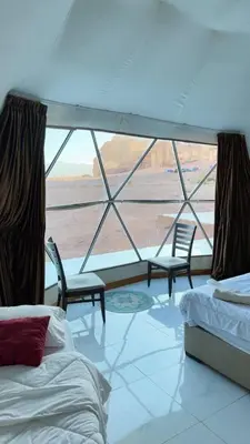a room with two beds and a large window at Silent Sands in Wadi Rum