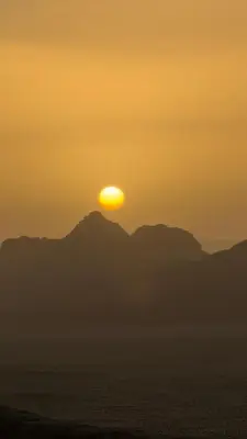 a sunset over the ocean with mountains in the background at Wadi rum camp Ausama in Wadi Rum