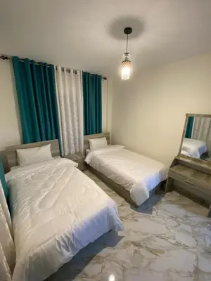a bedroom with two beds and a mirror at Travelers Choice Apartment Near Petra in Wadi Musa