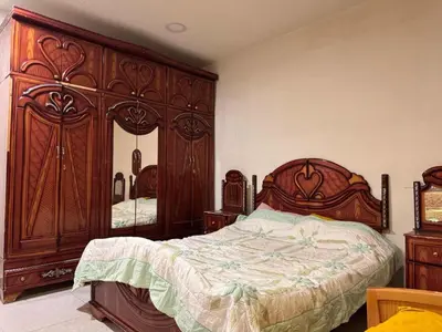 a bedroom with a large wooden bed and a large mirror at Hana Home in Amman