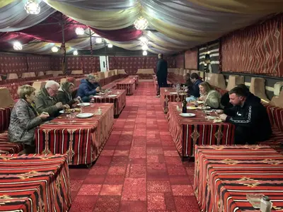 a group of people sitting at tables in a restaurant at Hillawi Desert Camp Wadi Rum in Disah