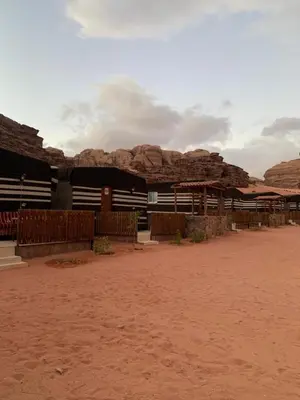 a building in the desert with mountains in the background at Hillawi Desert Camp Wadi Rum in Disah