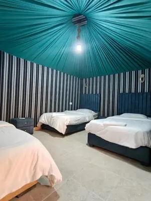 a room with two beds and a blue ceiling at Hillawi Desert Camp Wadi Rum in Disah