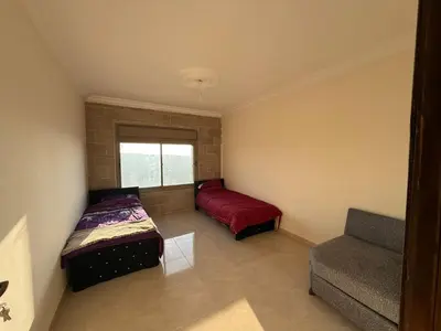 a bedroom with two beds and a couch and a window at شقه للإيجار عجلون -رأس منيف in Ajloun